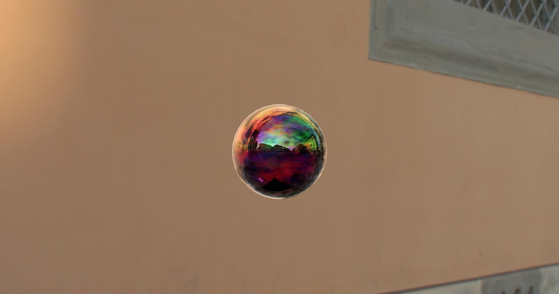 A shiny floating sphere with an iridescent multicolored sheen. It reminds you of a Christmas tree ornament. You can see a reflection of a city scene in it.